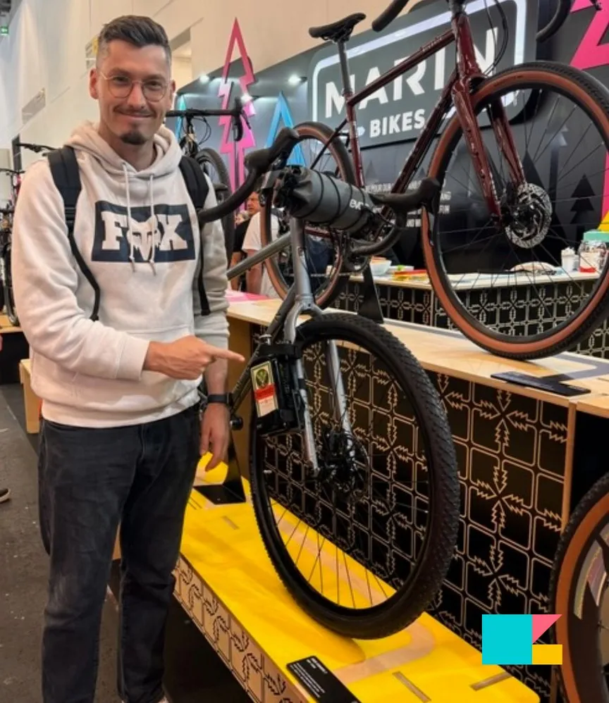 Ein Mitarbeiter der C3 marketing agentur steht auf der Eurobike 2024 in Frankfurt an einem Messestand und zeigt auf ein ausgestelltes Fahrrad.