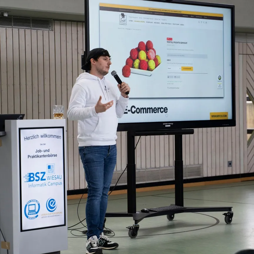 Ein Mitarbeiter der C3 marketing agentur hält einen Vortrag bei der Job- und Praktikantenbörse des BSZ Wiesau. Im Hintergrund ist eine Präsentation zu einem E-Commerce-Projekt zu sehen.